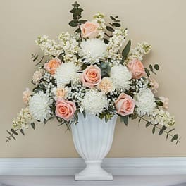 White and blush floral arrangement in a white pedestal vase