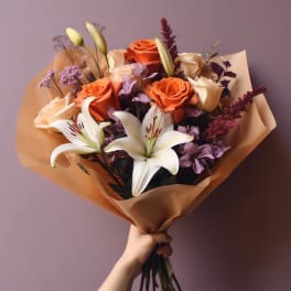 Bouquet of orange roses and white lilies wrapped in tan paper