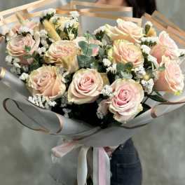 Bouquet of pale pink roses wrapped in translucent paper with ribbon