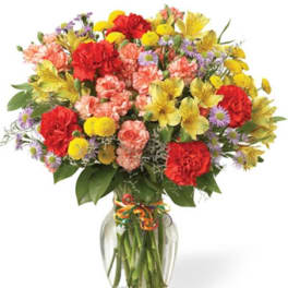 Mixed bouquet of red, yellow, pink, and purple flowers in a glass vase