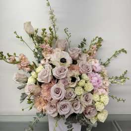 Large pastel floral arrangement in a white vase with roses and anemones