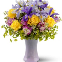 Yellow roses and purple iris in a lavender vase