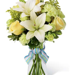 Bouquet of white lilies and pale yellow roses in a clear vase