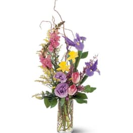 Tall mixed bouquet in a clear glass vase with purple, pink, and yellow flowers