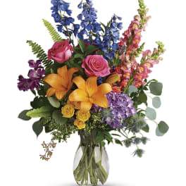 Colorful bouquet of lilies, roses, hydrangea, and snapdragons in a glass vase
