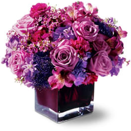 Purple and pink rose bouquet in a square glass vase