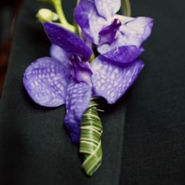 Purple orchid boutonniere on a dark suit lapel