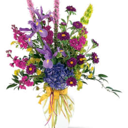 Mixed bouquet in a clear glass vase with purple, pink, yellow, and blue flowers