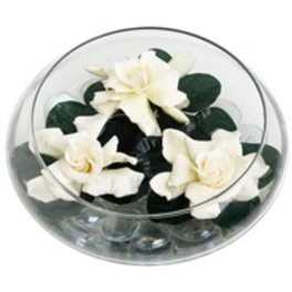 White flowers arranged in a clear round box with dark green accents