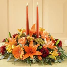 Orange floral centerpiece with two red taper candles