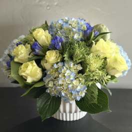 Yellow roses and blue hydrangeas in a white vase