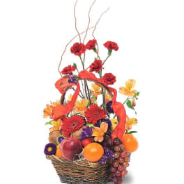 Basket arrangement with red and orange flowers, fruit, and ribbon