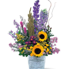 Mixed bouquet with sunflowers and purple flowers in a metal bucket
