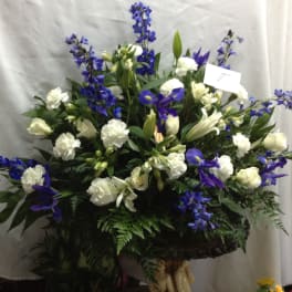 Large white and blue floral arrangement in a pedestal container