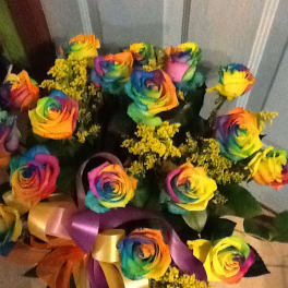 Bouquet of rainbow-colored roses with yellow filler flowers and satin ribbons