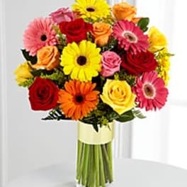 Mixed bouquet of gerbera daisies and roses in a clear vase