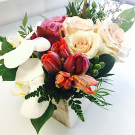 Mixed bouquet with roses, tulips, and white calla lilies in a wooden box