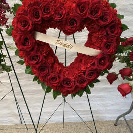 Heart-shaped red rose and carnation wreath with a ribbon reading Daddy