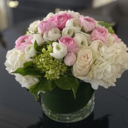 Pink and white flowers arranged in a round glass vase