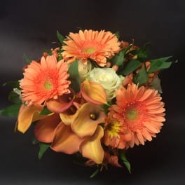 Orange gerbera daisies and calla lilies with white roses in a bouquet