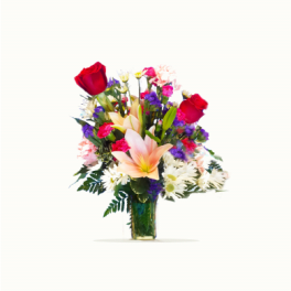 Mixed bouquet of red roses, lilies, and daisies in a glass vase