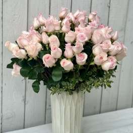 Bouquet of pale pink roses in a tall white vase