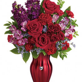 Red roses and purple flowers arranged in a red vase