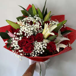 Bouquet of red roses and white lilies wrapped in red paper