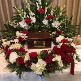 Funeral wreath with red and white flowers around a wooden urn