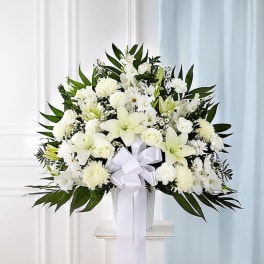White floral standing arrangement with a ribbon bow in a vase