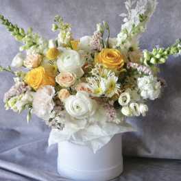 Mixed bouquet of yellow and white flowers in a white hat box