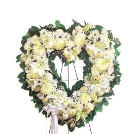 Heart-shaped white floral wreath on a stand with a ribbon