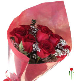 Bouquet of red roses with white filler flowers wrapped in pink paper