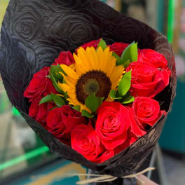 Bouquet of red roses with a yellow sunflower wrapped in black paper