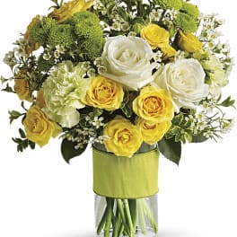 Yellow and white roses in a clear glass vase with green button mums