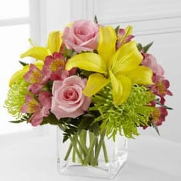 Pink roses and yellow lilies in a clear glass vase