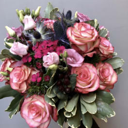 Bouquet of pink roses and lisianthus with dark thistle accents