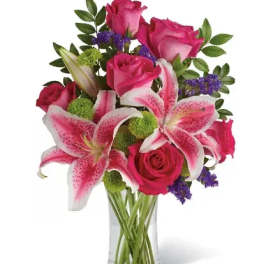 Pink roses and lilies arranged in a clear glass vase