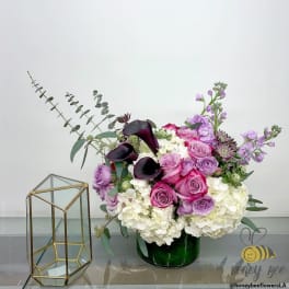 Pink and purple floral arrangement in a green vase beside a glass terrarium