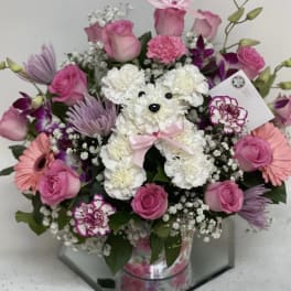 Pink and white flower arrangement with a teddy bear in a mirrored vase