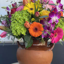 Colorful mixed bouquet in a terracotta vase with gerbera daisies and orchids