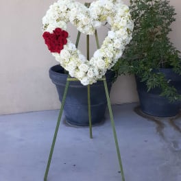 Heart-shaped white rose wreath with a red rose cluster on an easel