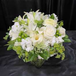 White lilies, roses, and calla lilies in a glass vase