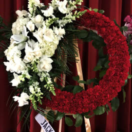 Large red and white floral wreath on a stand with a ribbon