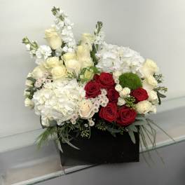 Mixed bouquet of red and white roses with white hydrangeas in a black box