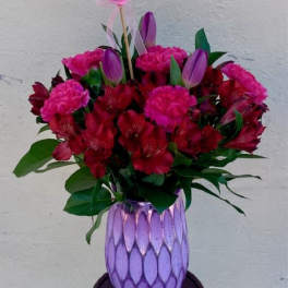 Bouquet of red and pink flowers in a purple vase with a heart balloon