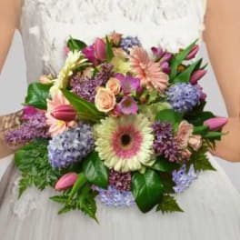 Bride holding a pastel bouquet with gerbera daisies, tulips, and hydrangeas