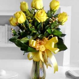 Yellow roses arranged in a glass vase with a yellow ribbon