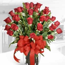 Bouquet of red roses in a clear glass vase with a red bow