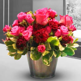 Pink and red roses arranged in a metal vase